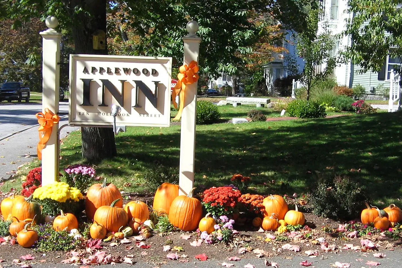 The Applewood Inn sign in autumn, surrounded by pumpkins and mums